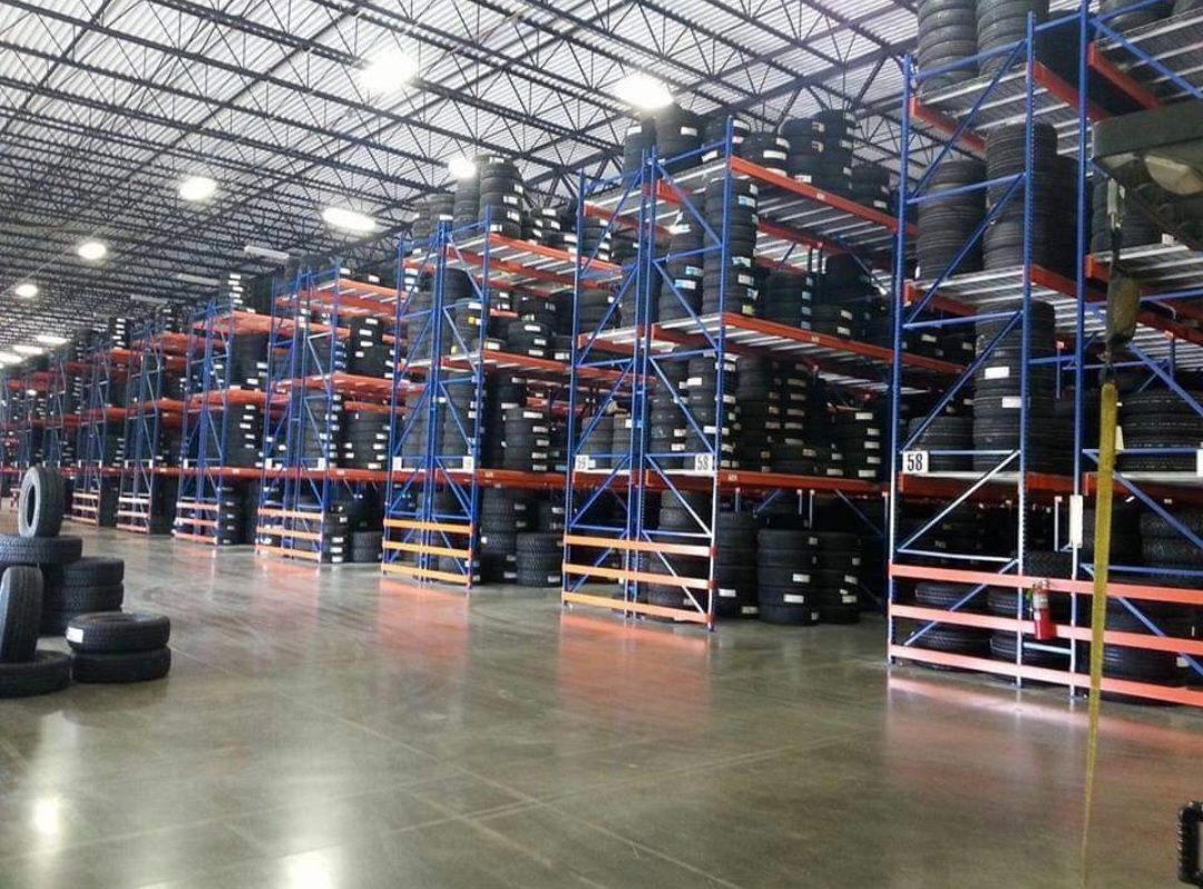 Empty warehouse with tall blue-and-orange storage racks and polished concrete floor.