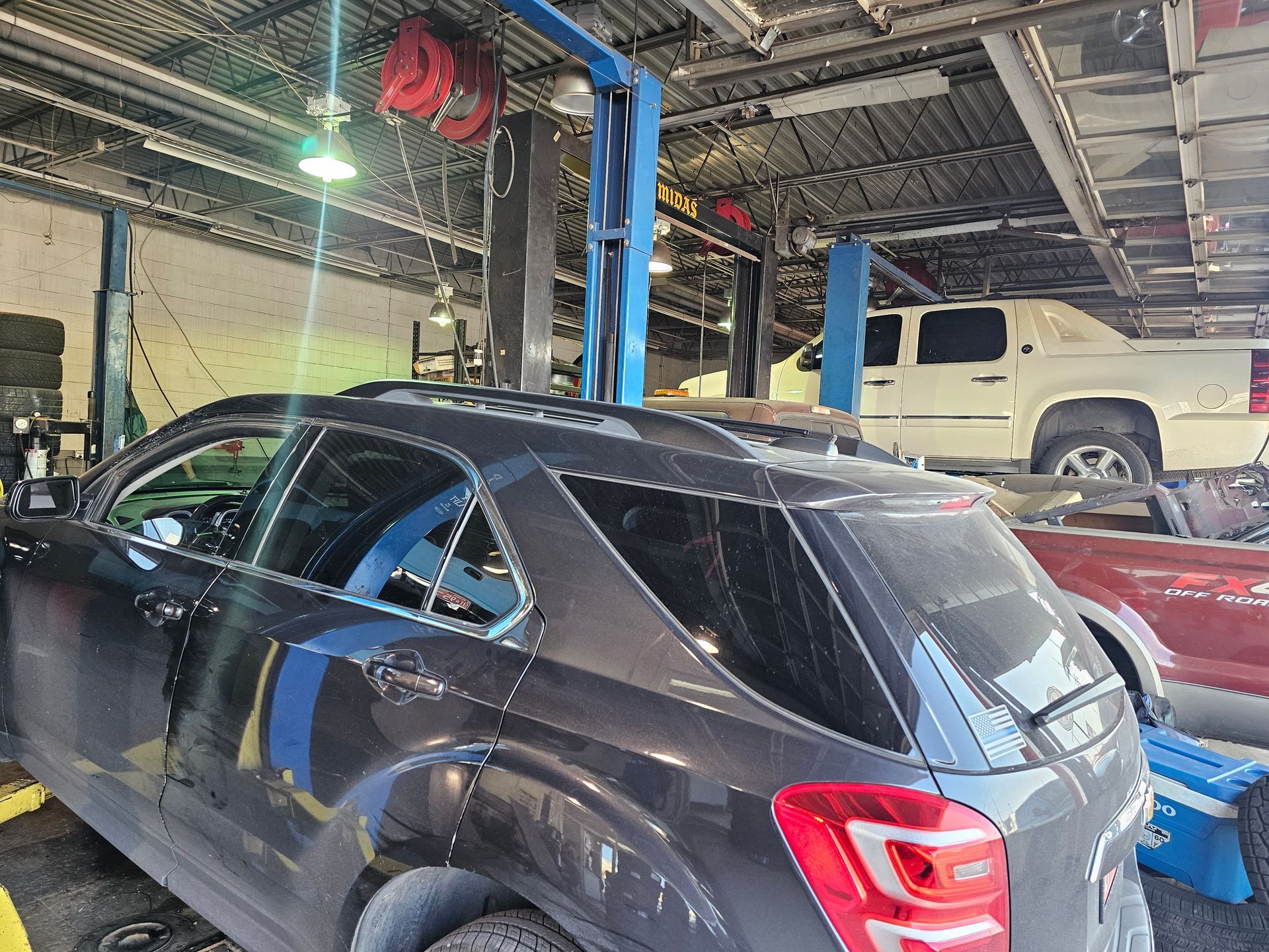 A dark gray SUV parked inside an auto repair shop with other vehicles visible in the background.