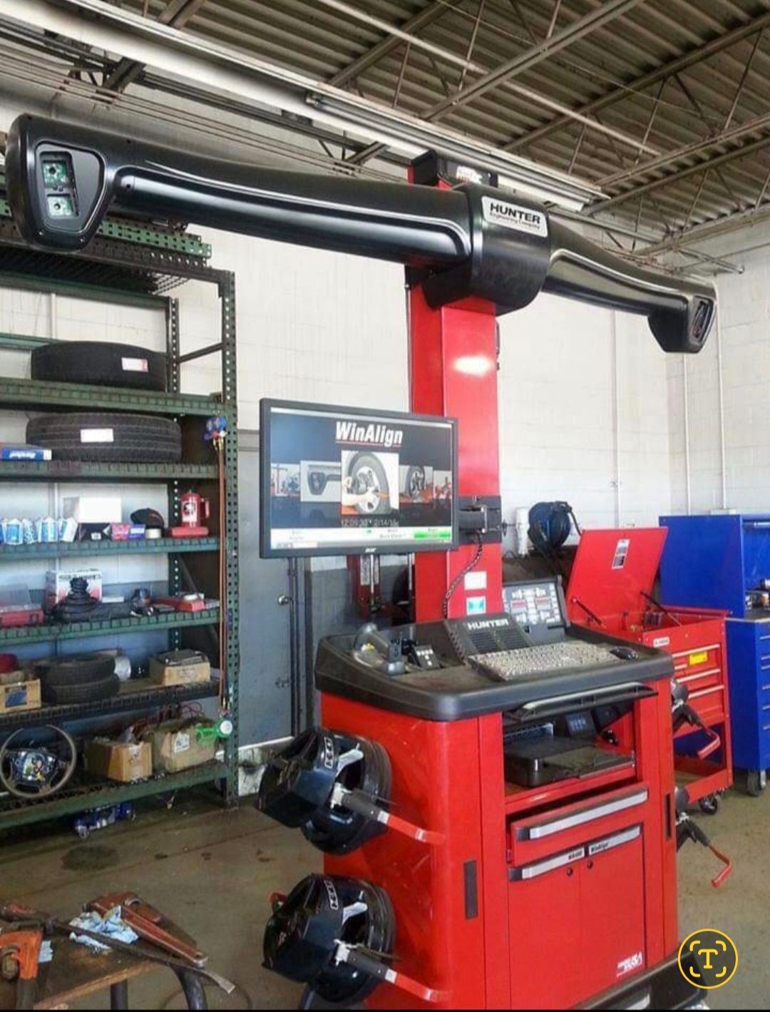 A Hunter wheel alignment machine with a red base and monitor stand, positioned in an automotive service shop.
