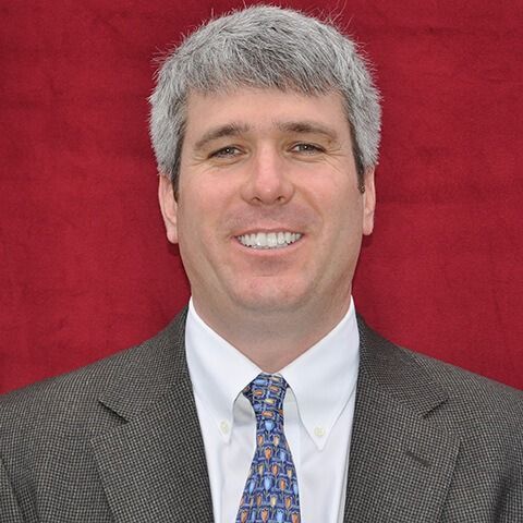 A man in a suit and tie is smiling for the camera