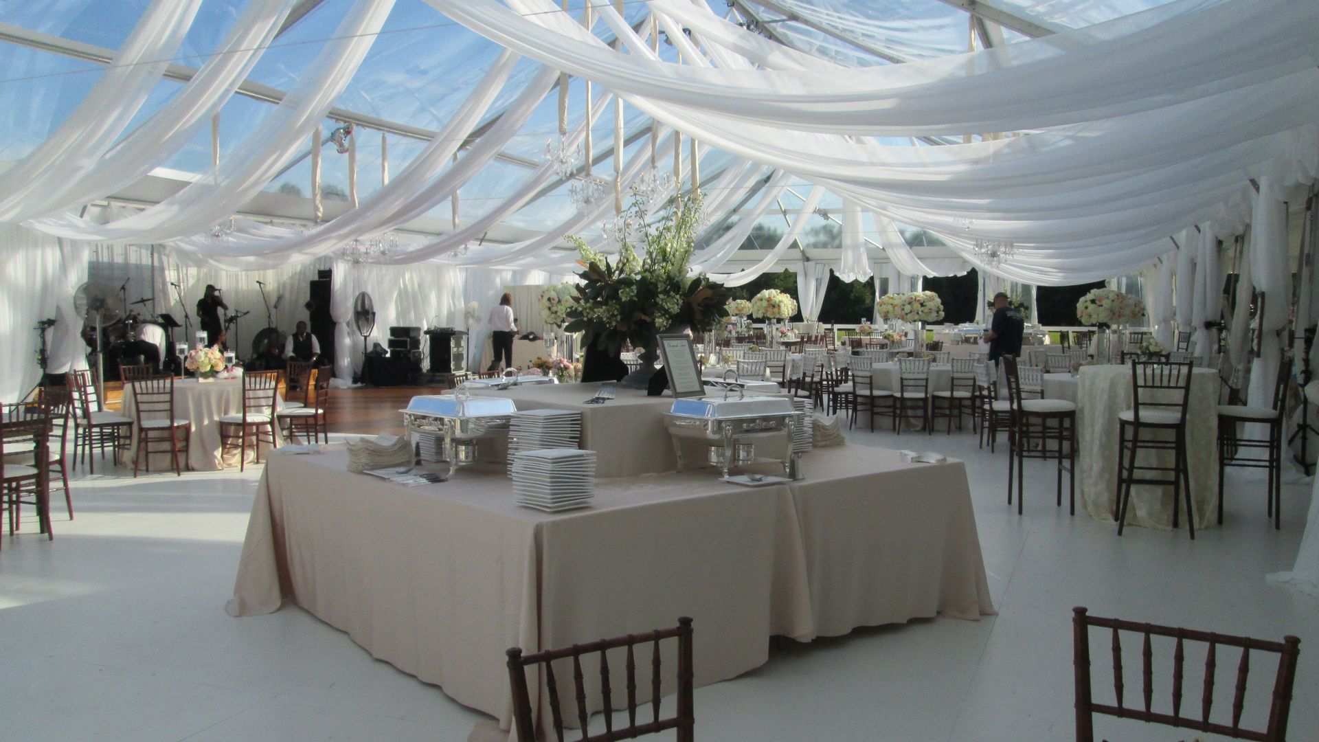 Elegant tented event space with draped white fabric, catering buffet, and tables.