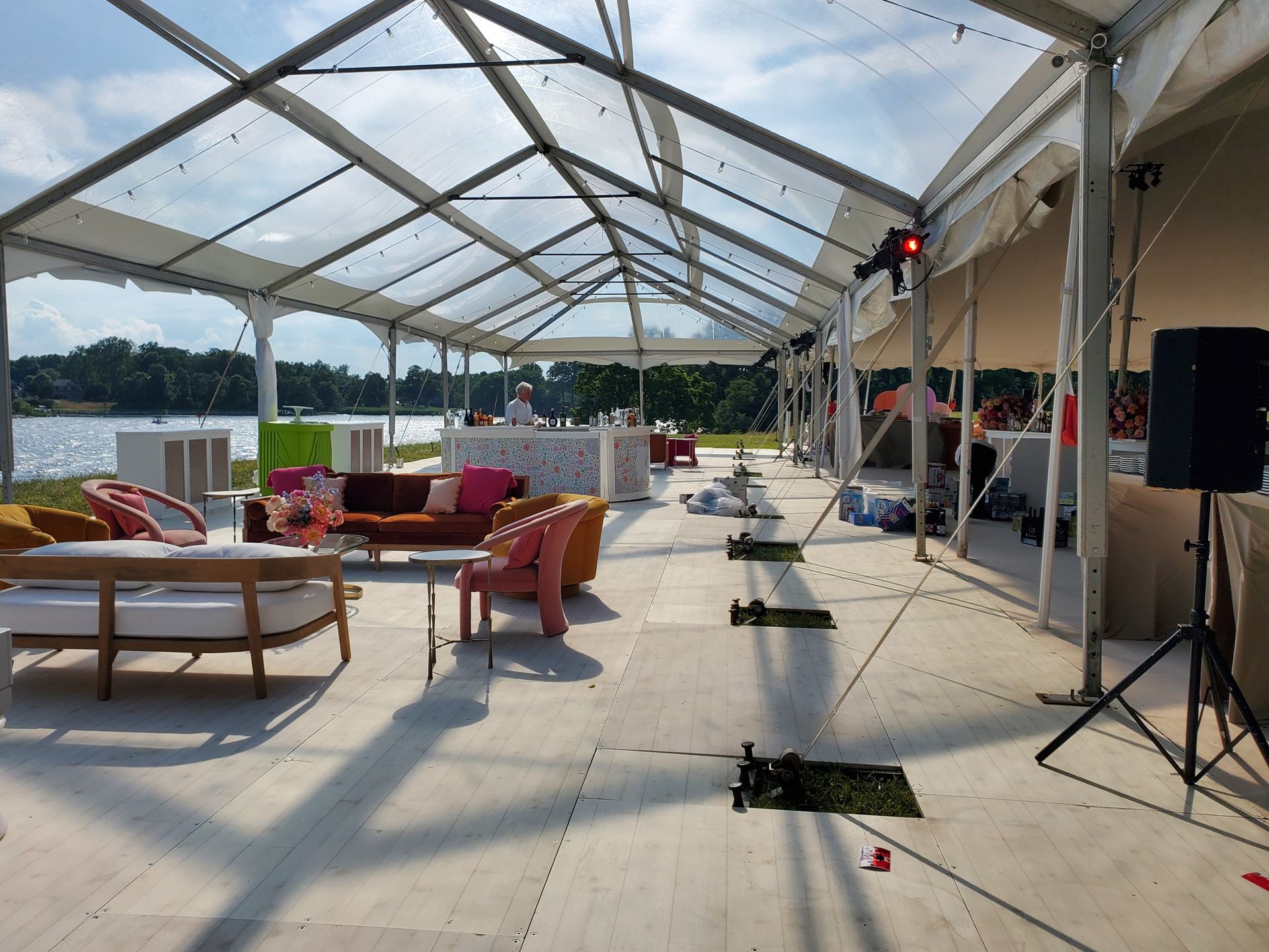 A large event tent with seating, a bar, and a lake view.