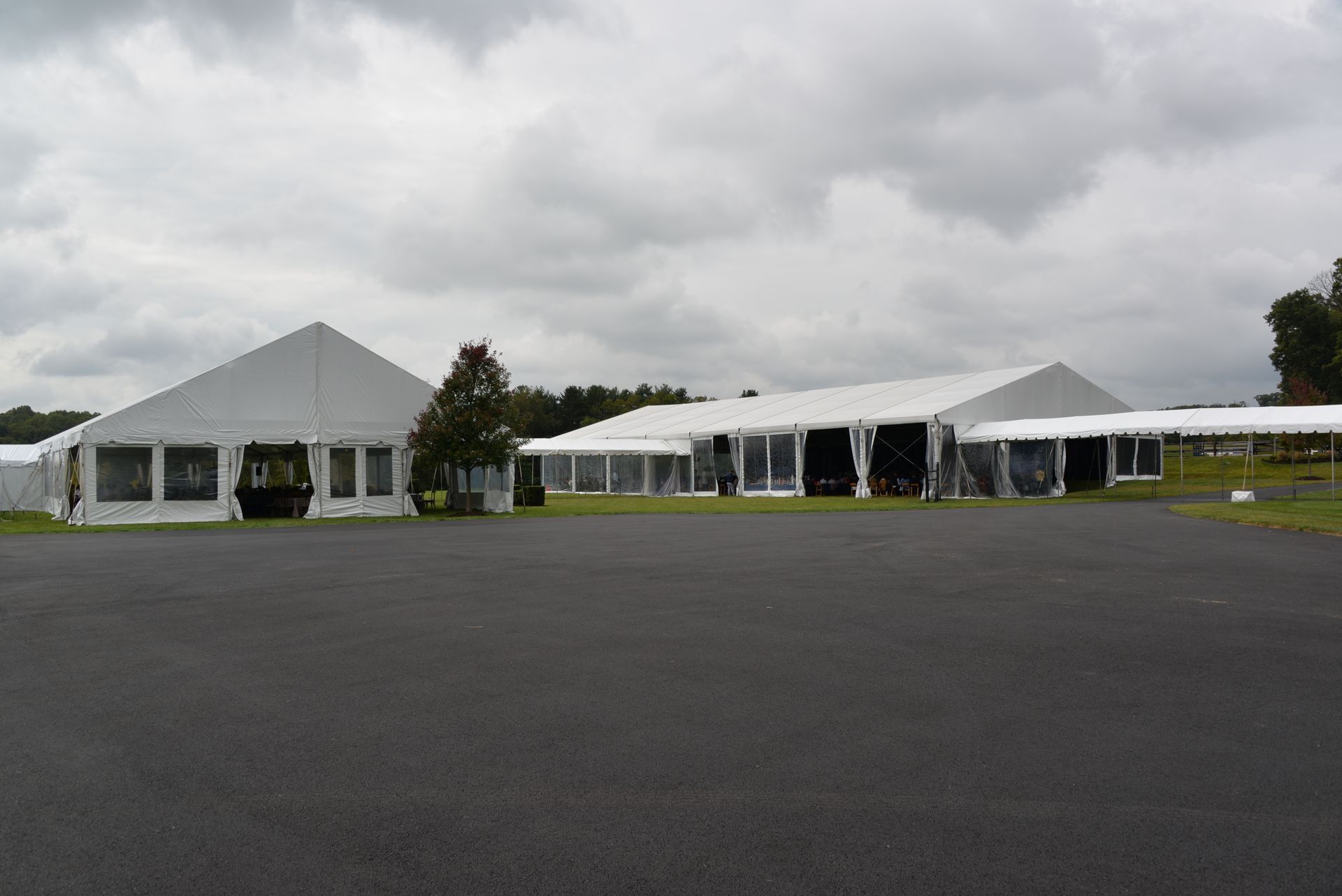 White event tents on an asphalt surface, under a cloudy sky.
