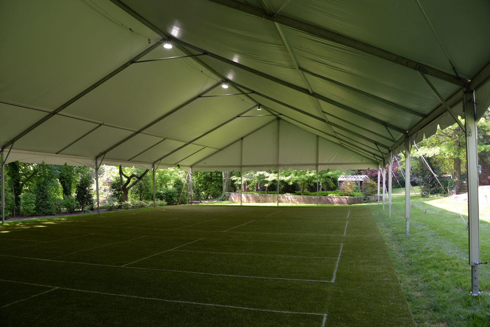 Inside a large, open-sided tent with a green floor, trees visible outside.