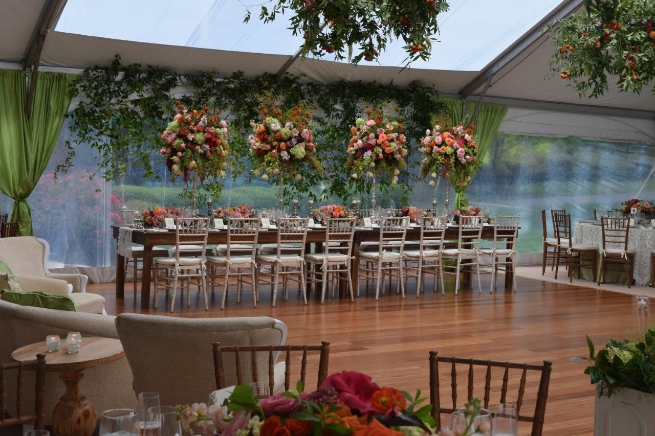 A tented event space with long tables, floral arrangements, and a dance floor.
