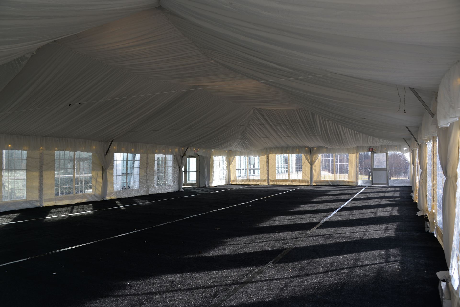 Inside a large white tent with black flooring and windowed walls.