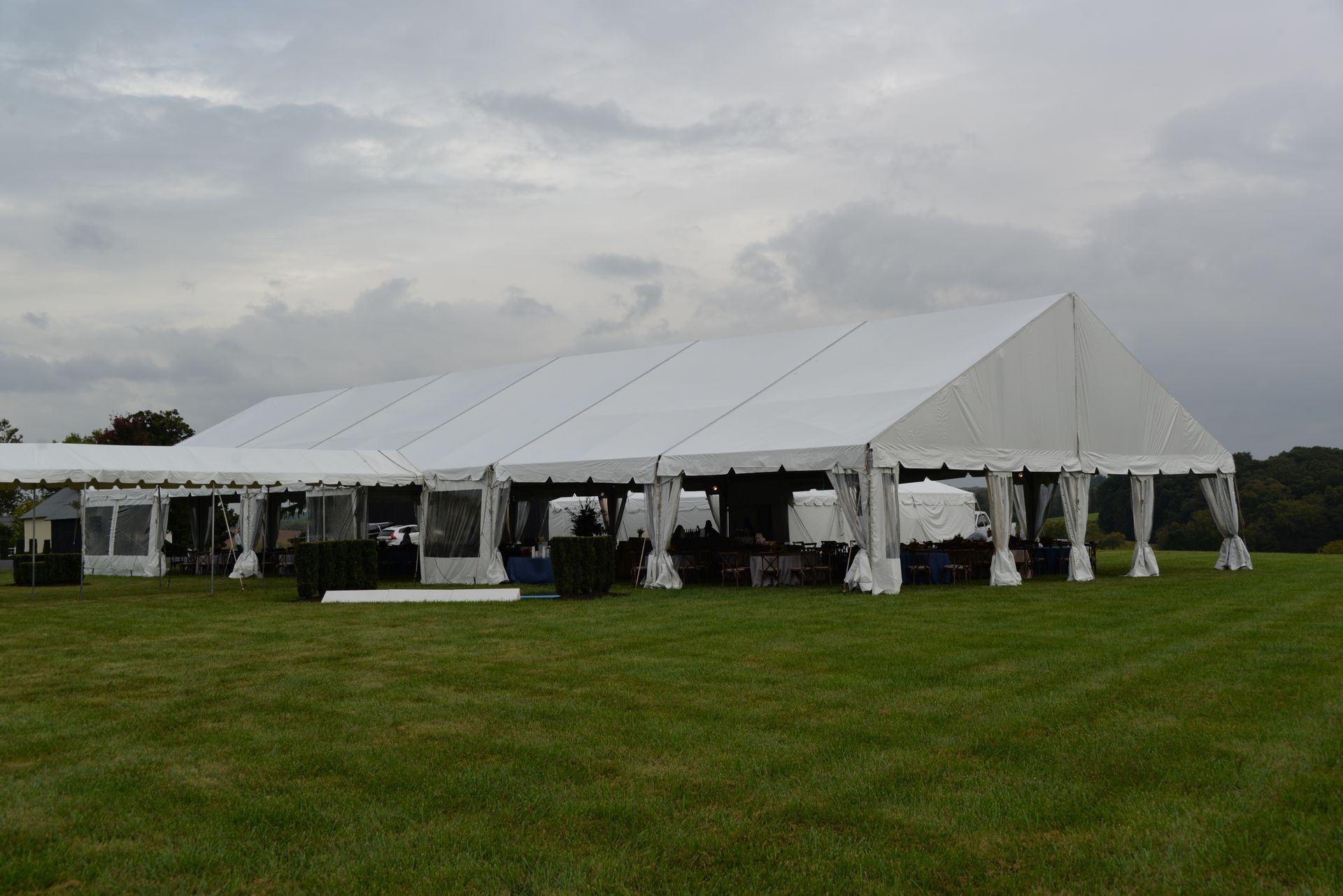 White tent set up on a grassy field under a cloudy sky, likely for an event.