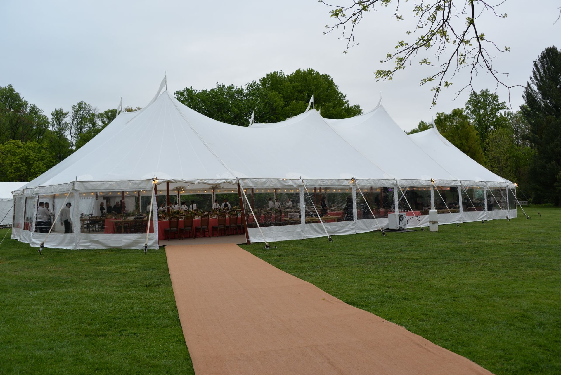 Large white tent on green grass, with a brown carpet path leading to the entrance.