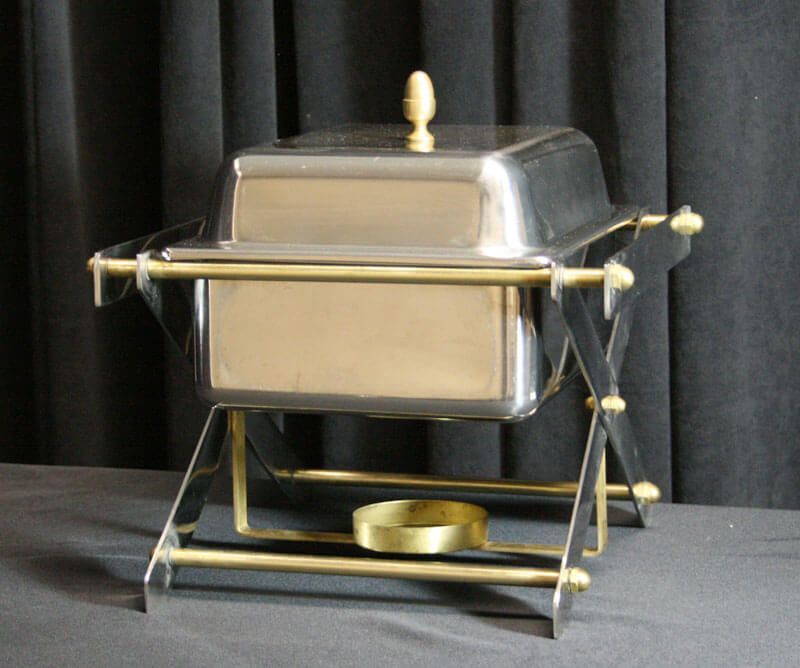Silver chafing dish with gold-colored stand and accents, against a dark background.