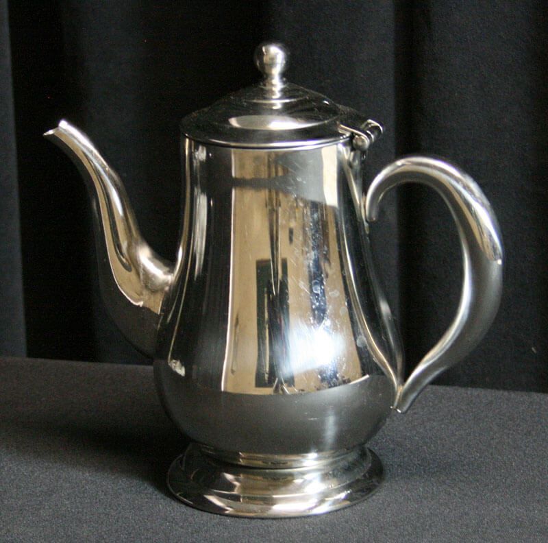 Silver coffee pot with a curved handle and spout, on a dark surface.