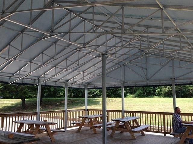 Covered outdoor dining area with picnic tables on a wooden deck.