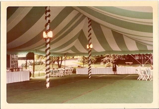 A green and white striped tent with tables and chairs underneath