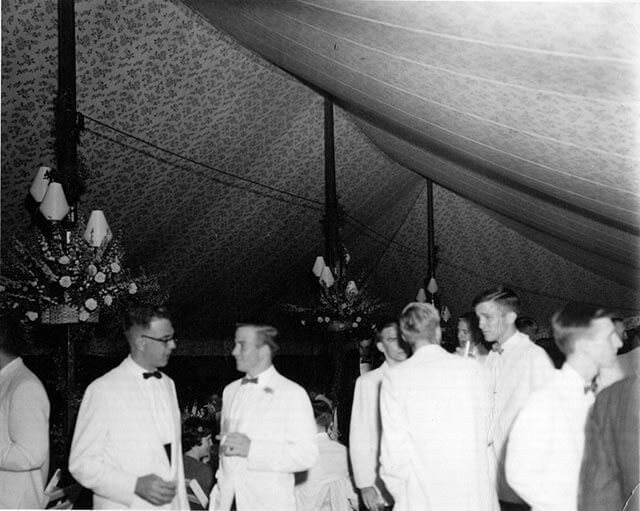 A black and white photo of a group of people standing under a tent