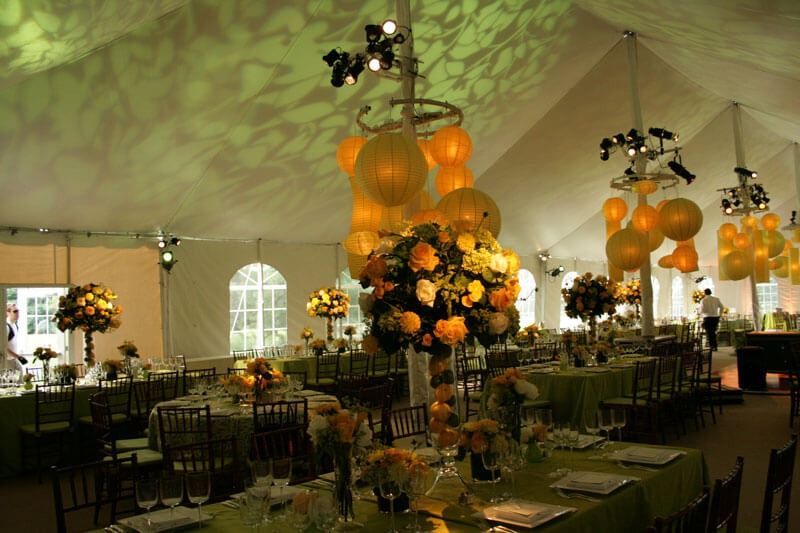 A large tent with tables and chairs set up for a wedding reception.