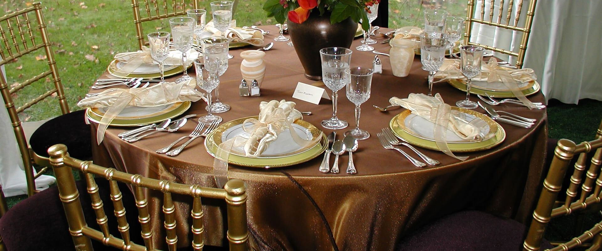 A table set for a wedding reception with gold chairs