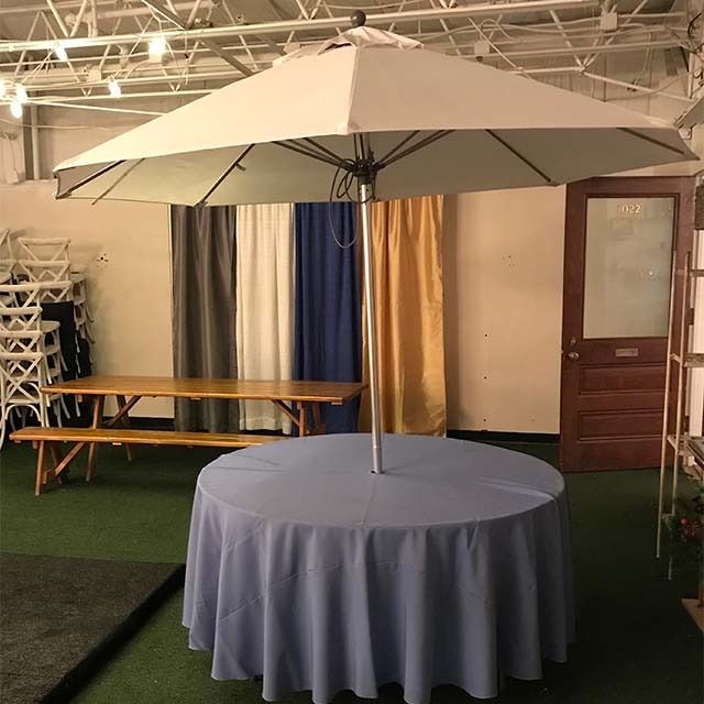 A round table with a blue tablecloth under an umbrella