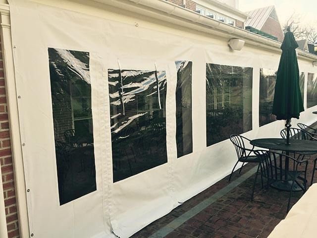 A patio area with tables and chairs under a tent with a green umbrella.