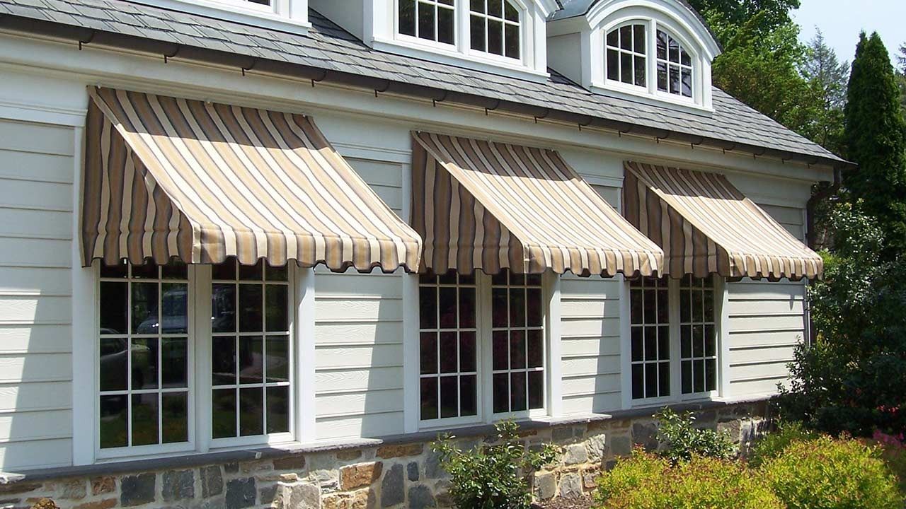 A white house with striped awnings on the windows
