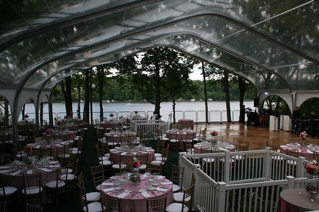 Tables and chairs are set up under a clear tent