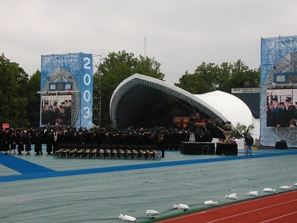 A group of people are standing in front of a stage that says 2003