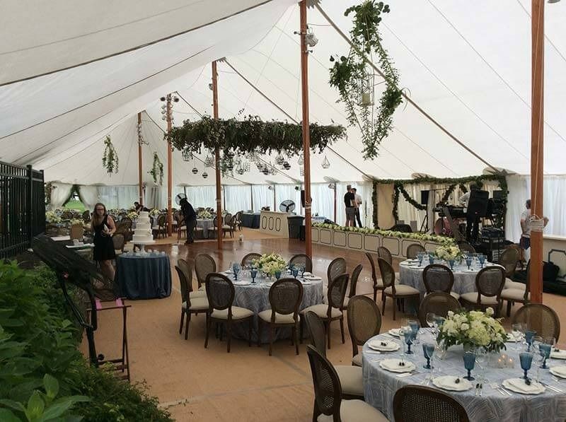 A large tent with tables and chairs set up for a wedding reception