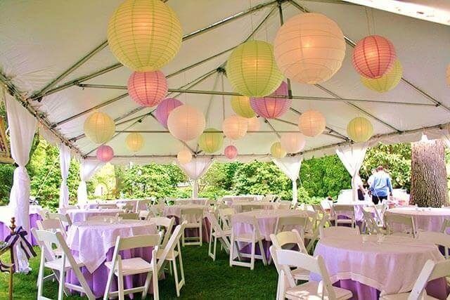 Tables and chairs under a tent with lanterns hanging from the ceiling