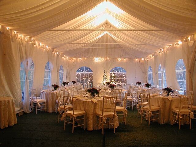 A large tent with tables and chairs set up for a wedding reception