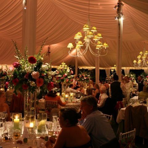 A group of people are sitting at tables under a tent