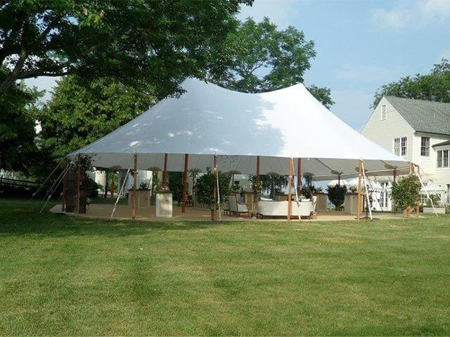 A large white tent is sitting in the middle of a lush green field.
