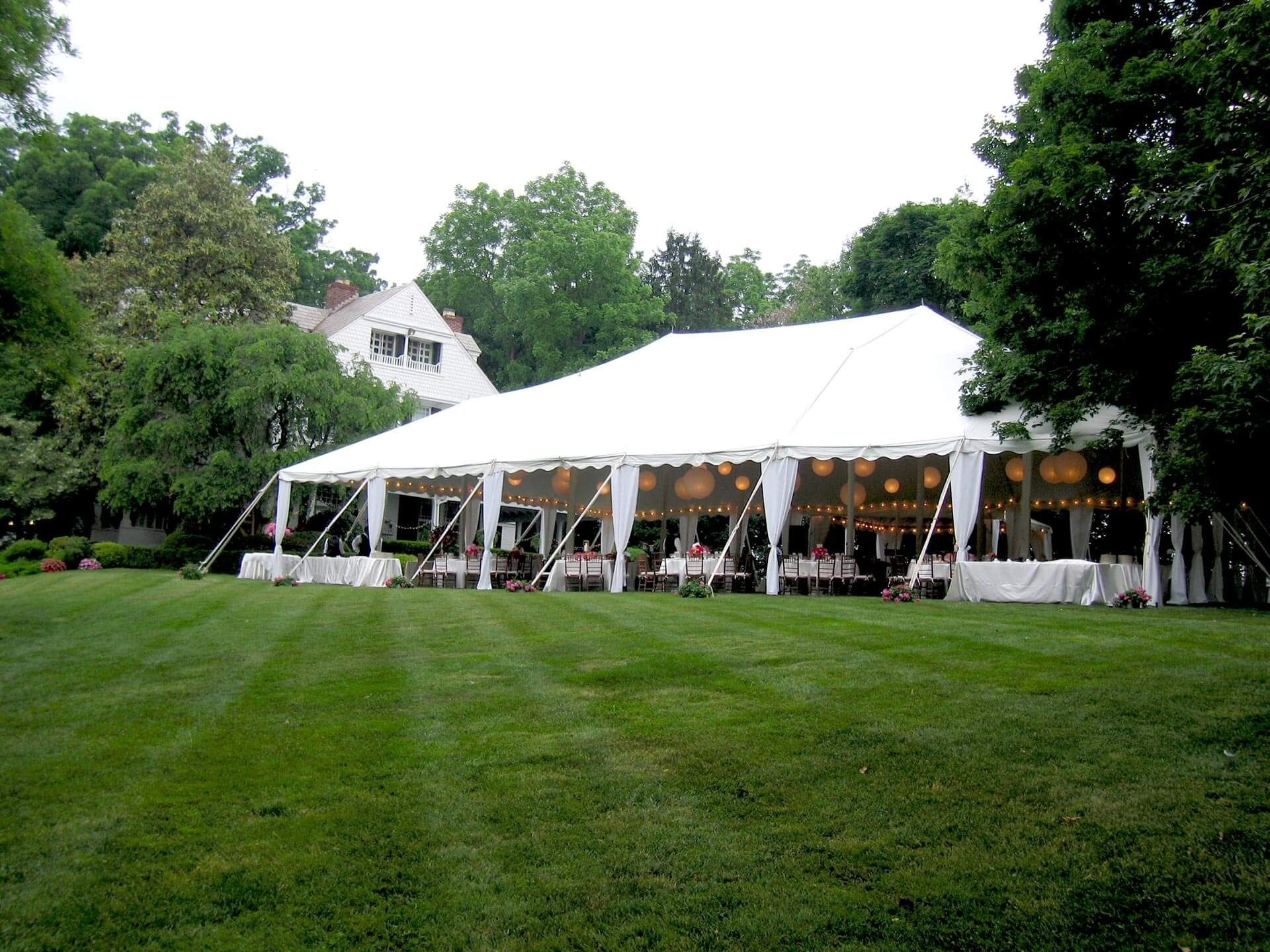 A large white tent is sitting in the middle of a lush green field.