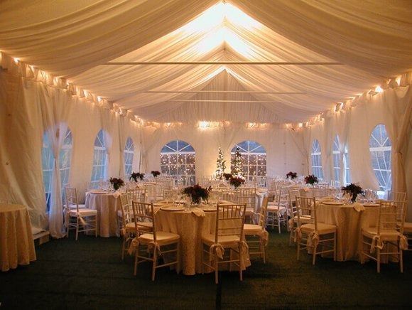 A large tent with tables and chairs set up for a wedding reception