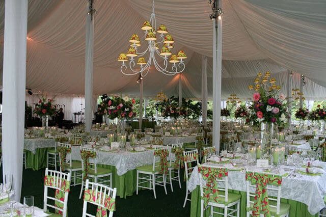 A large tent with tables and chairs set up for a wedding reception.