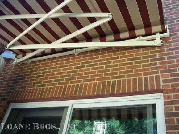 Red and cream striped awning over a window on a brick wall.