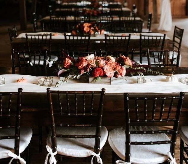 Wedding reception tables with floral centerpieces and dark wood chairs