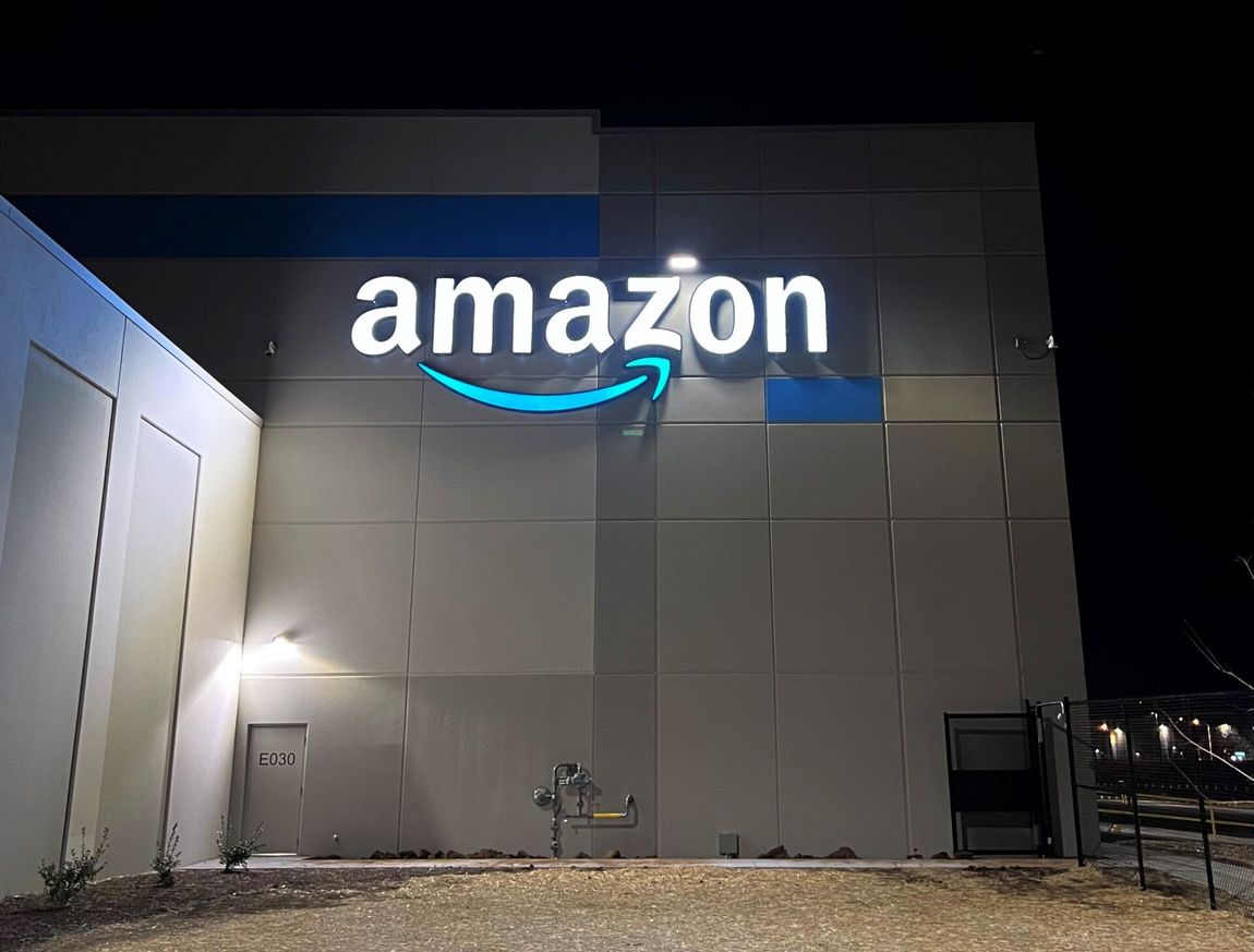 A large amazon sign is lit up at night on the side of a building.