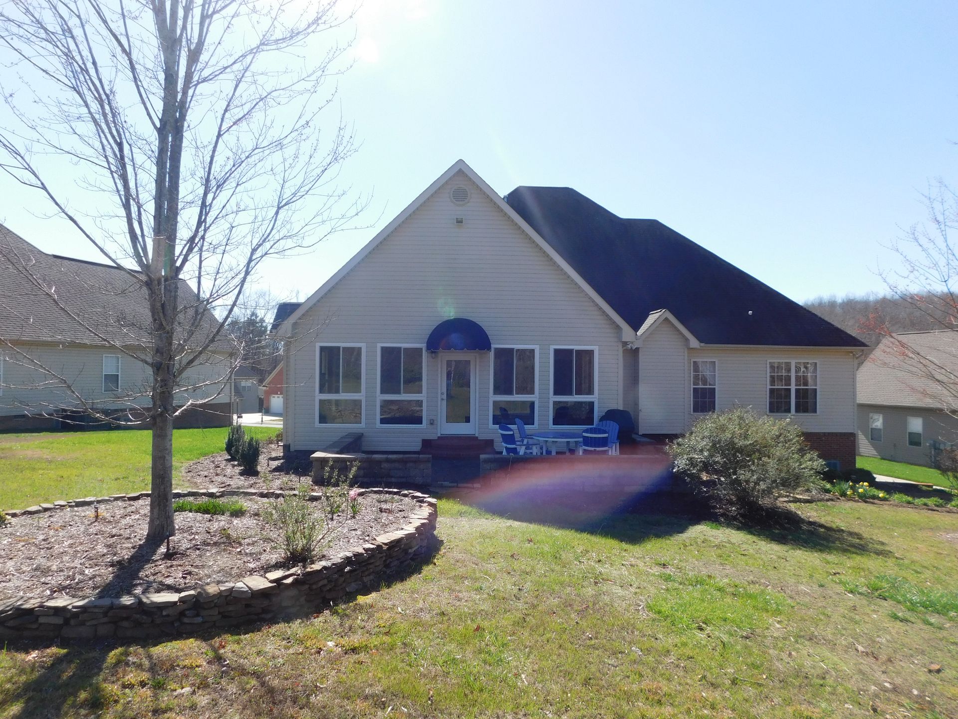 A white house with a black roof and a blue awning
