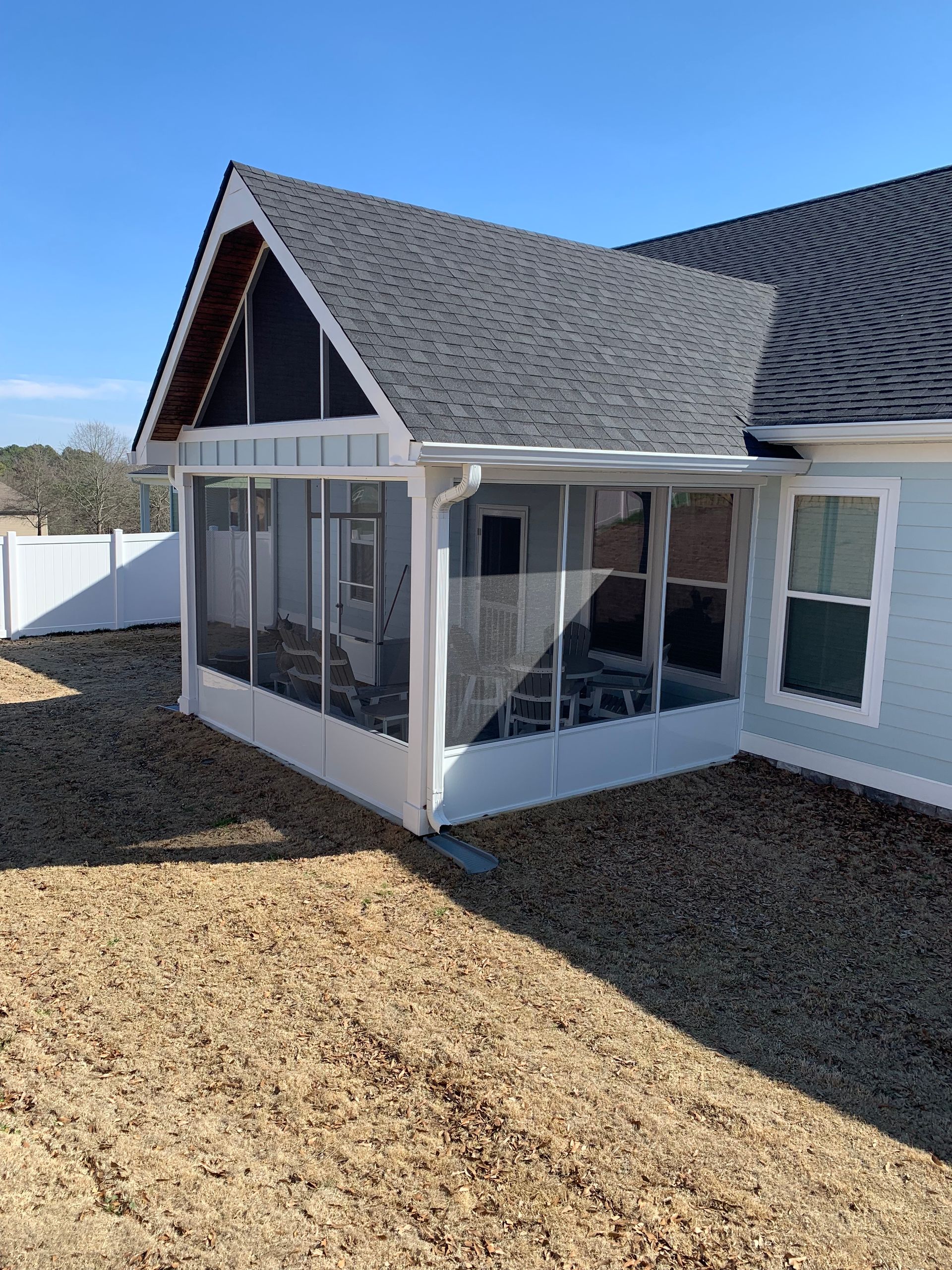 A screened in porch in the backyard of a house.