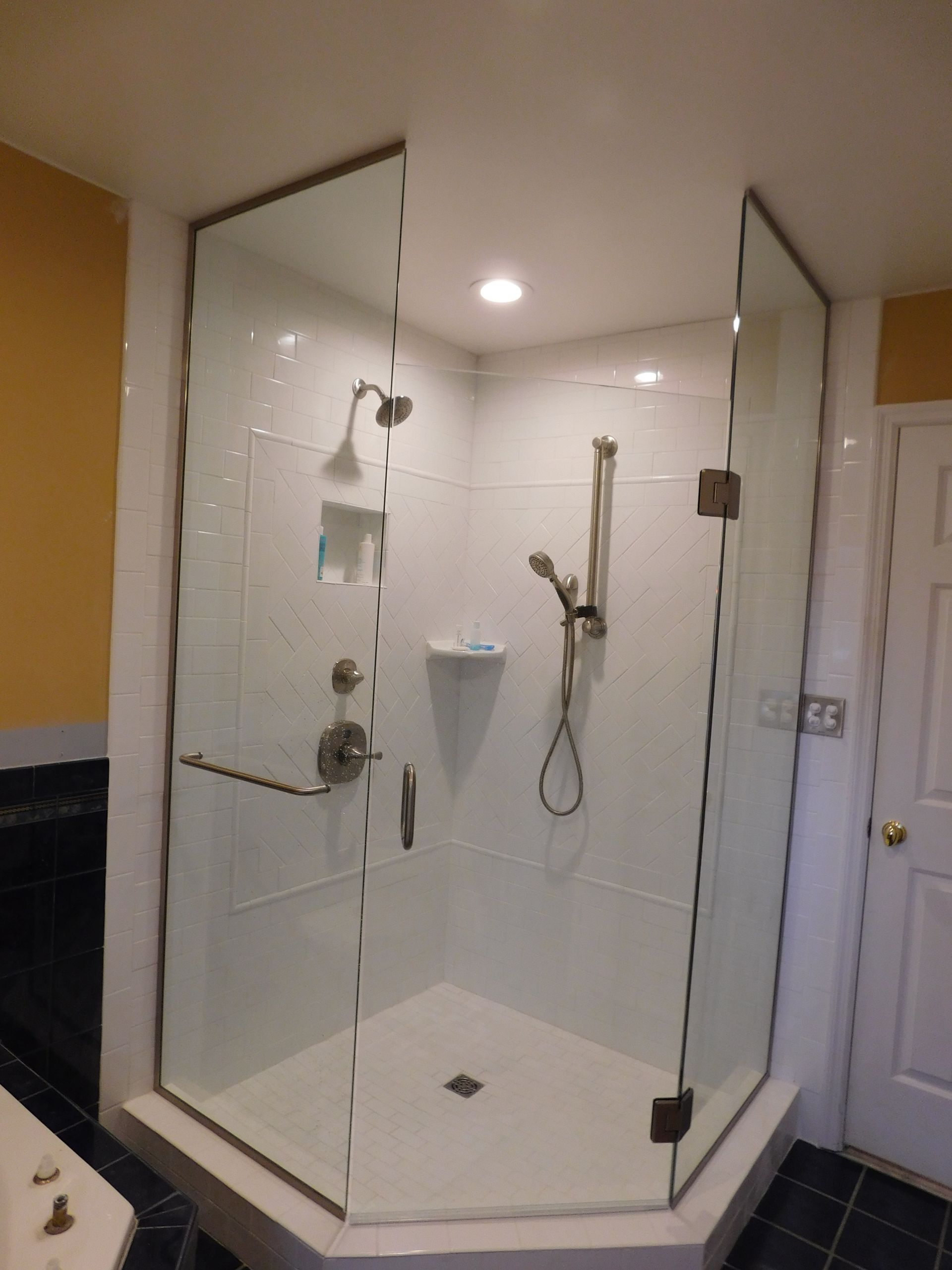 A bathroom with a walk in shower with a glass door