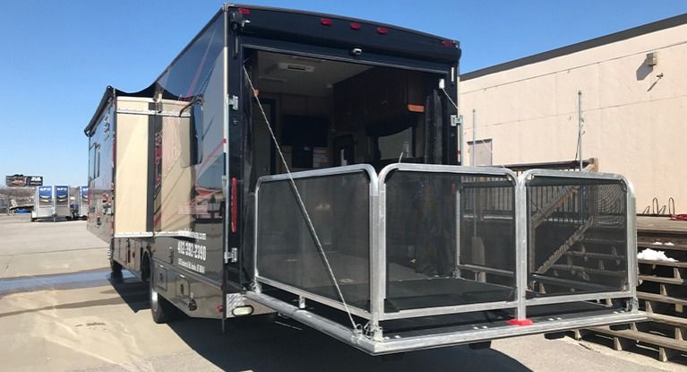 RV with a black ramp extended, showing an open back door and ramp.