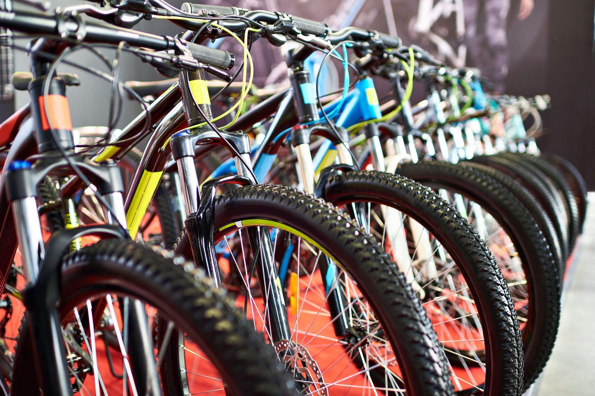 Row of mountain bikes with black tires and colorful frames, indoors.