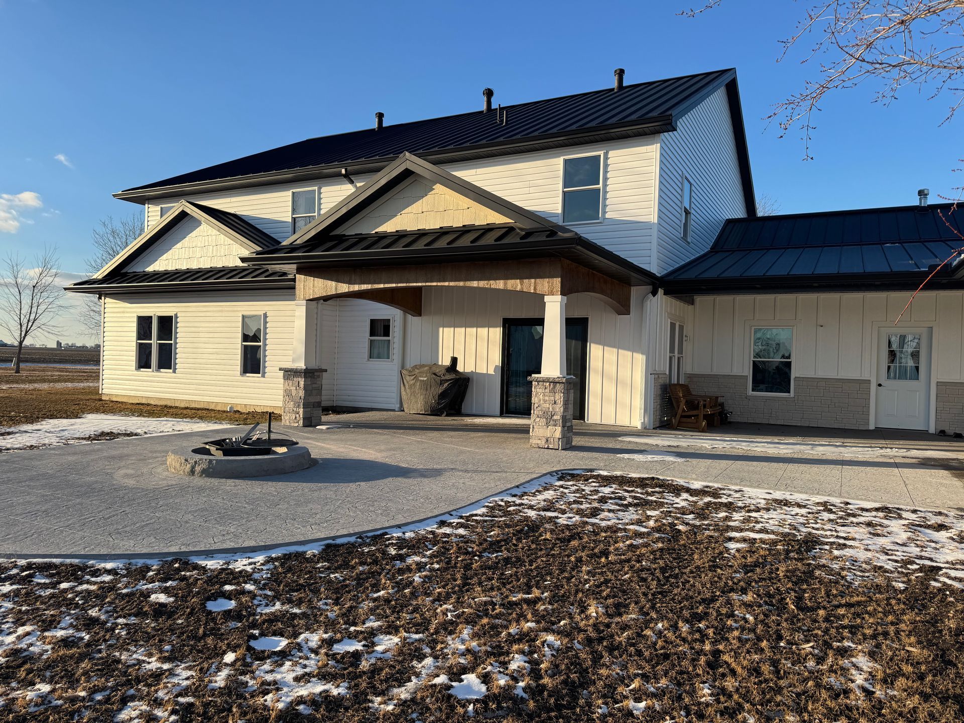 A large white house with a fire pit in front of it.