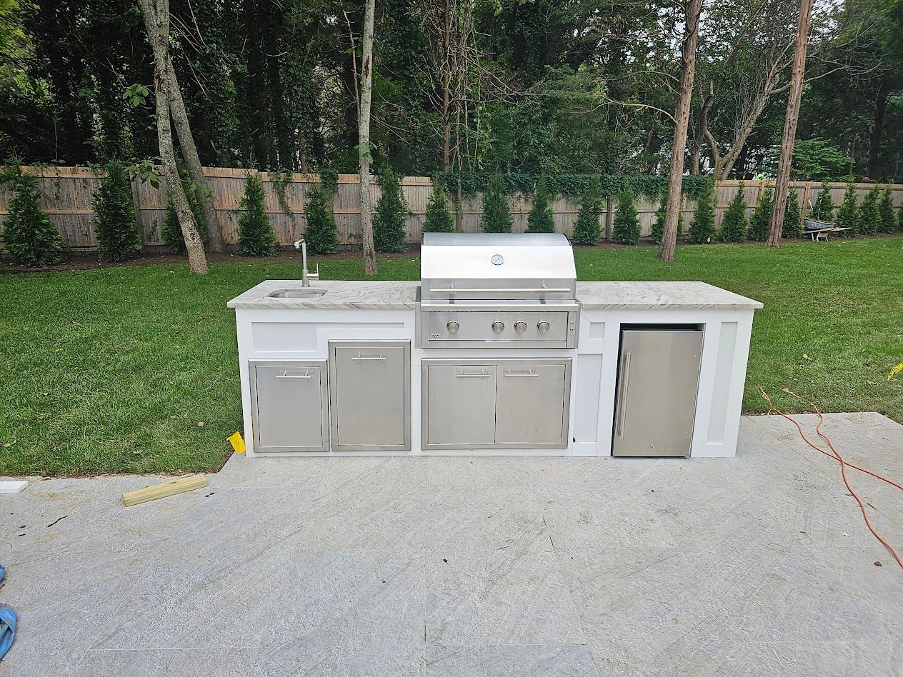 Outdoor grilling station with stainless steel appliances set on a concrete countertop.