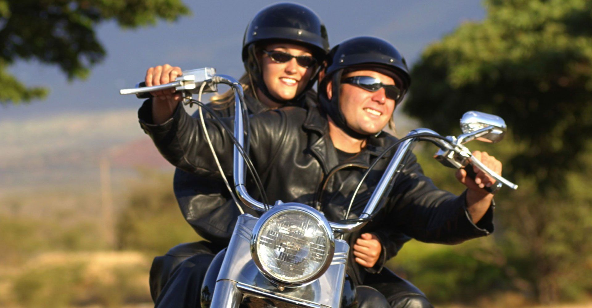 Man and woman wearing helmet and sun glasses riding a motorcycle