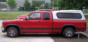 Aluminum topper on red pick-up at parking lot