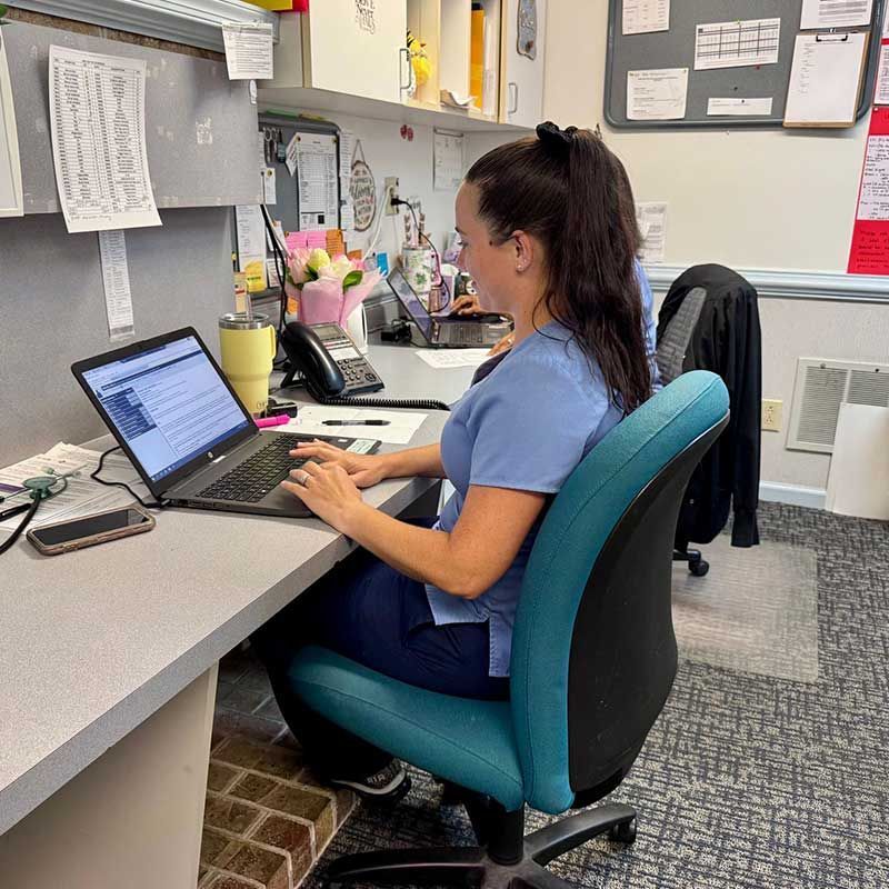 a woman is sitting at a desk using a laptop computer