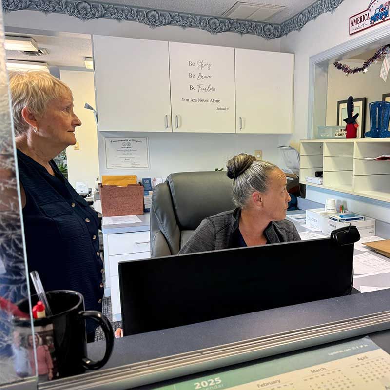 two women are sitting at a desk in front of a computer