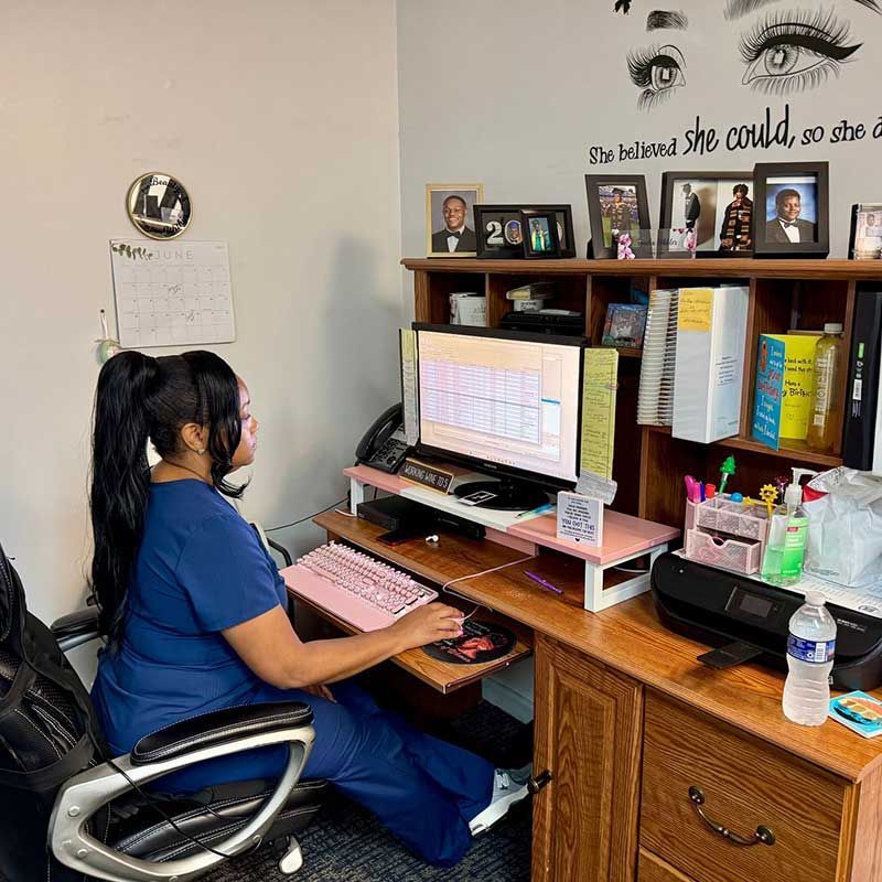 a woman is at a desk in front of a computer