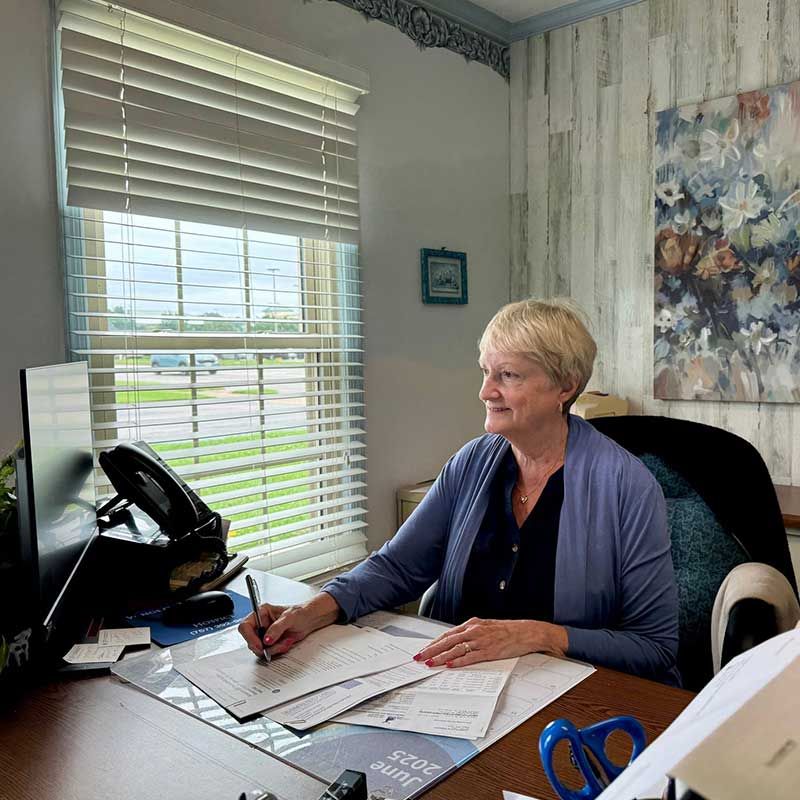 a woman is sitting at a desk in front of a window