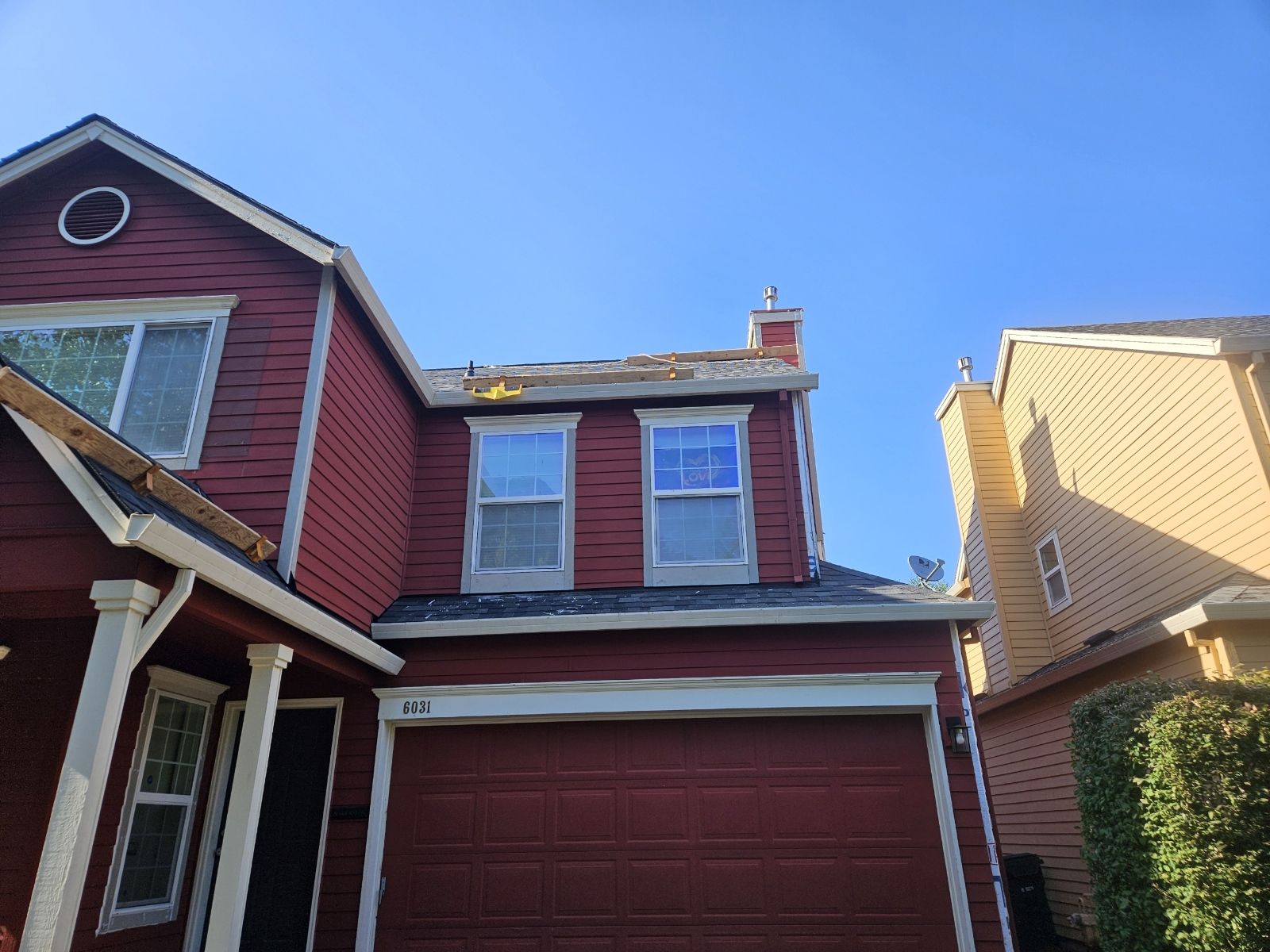 A red house with a garage and a blue sky in the background.