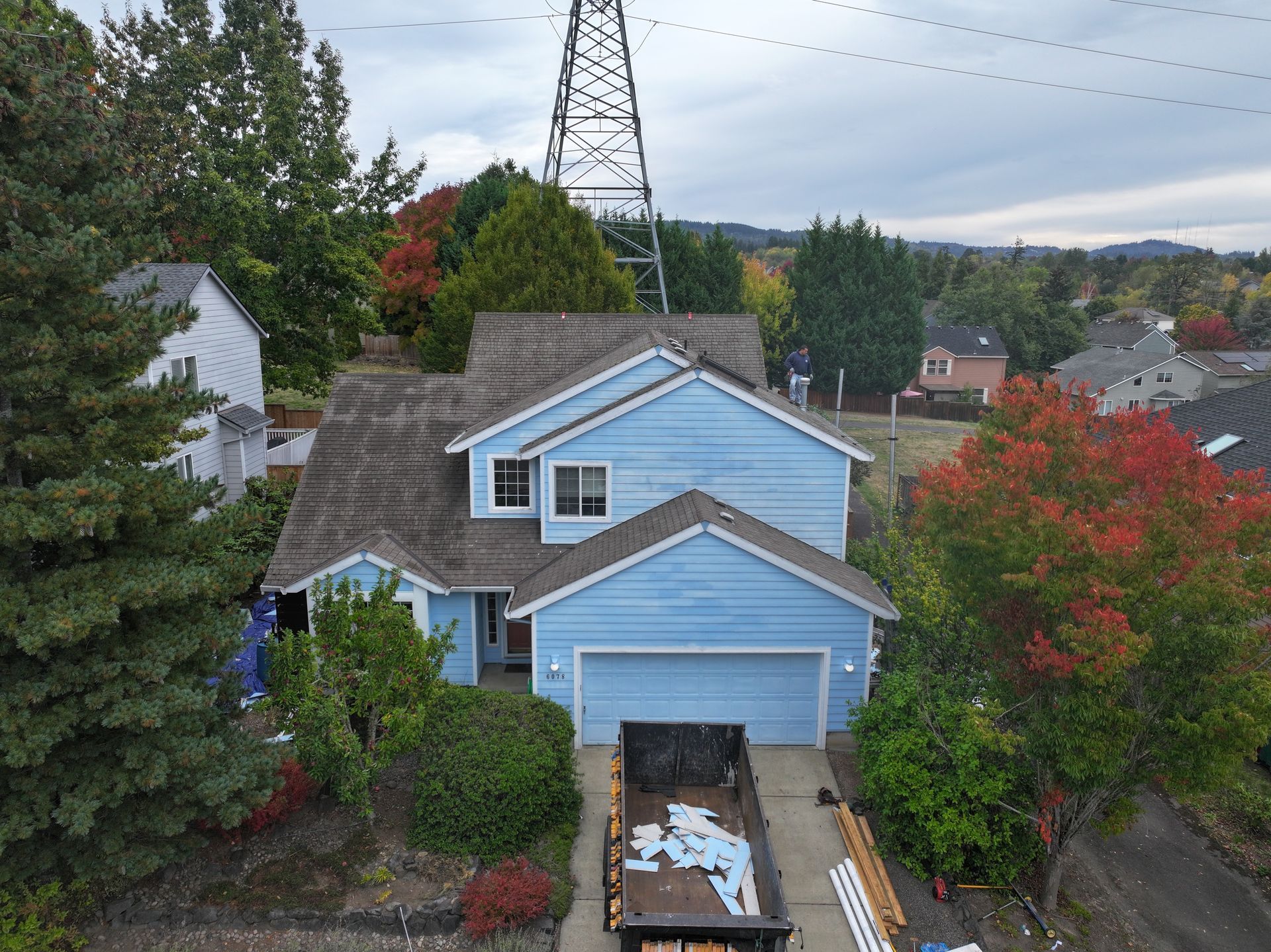 An aerial view of a blue house with a dumpster in front of it.